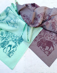 two final switchback cotton bandanas in backcountry mint and purple featuring artist Katie Jeanne Reim's prints