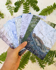 a hand holding final switchback's greeting cards featuring prints by artist Katie Jeanne Reim