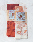 two final switchback cotton bandanas in Desert Nights cream and orange featuring artist Katie Jeanne Reim's prints