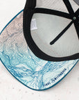 brim view of the final switchback trucker hat featuring artist Katie Jeanne Reim's Glacier Goat Summit print