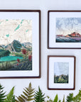 frames with final switchback by artist Katie Jeanne Ream prints on a white wall with some foliage