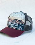 angle view of the final switchback trucker hat featuring artist Katie Jeanne Reim's three sisters print