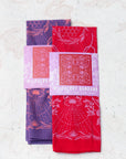 two final switchback cotton bandanas in wildberry red and wildberry purple featuring artist Katie Jeanne Reim's prints