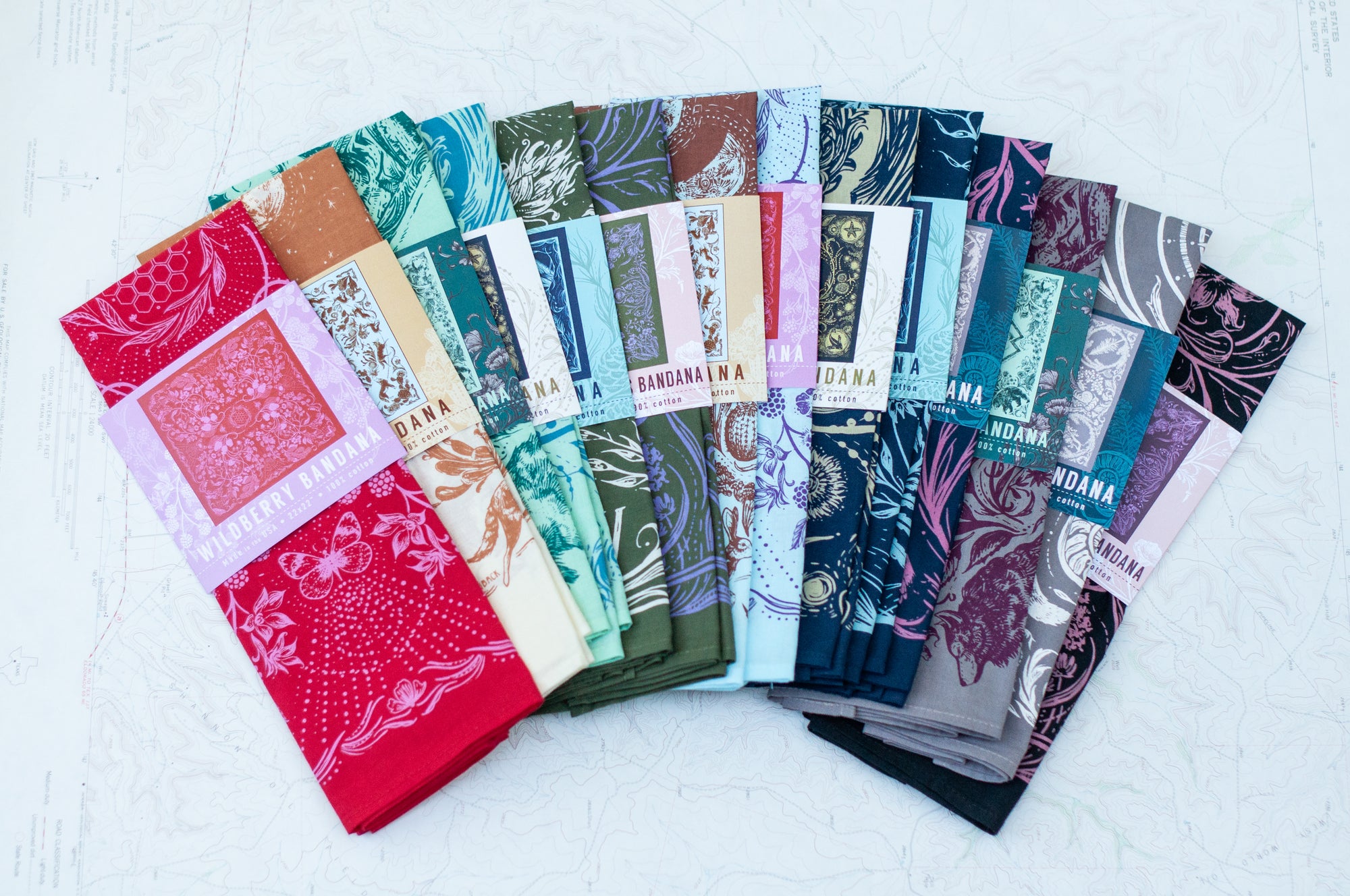 all of the final switchback cotton bandanas laid out in packages featuring artist Katie Jeanne Reim&#39;s prints