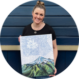final switchback artist Katie Jeanne Reim holding a print smiling at the camera