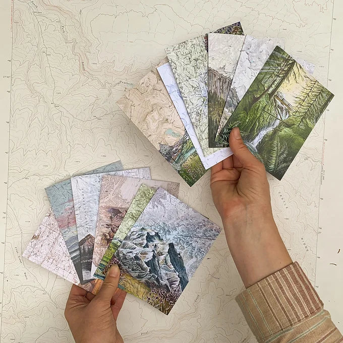 a hand holding final switchback&#39;s greeting cards featuring contours of national parks prints by artist Katie Jeanne Reim