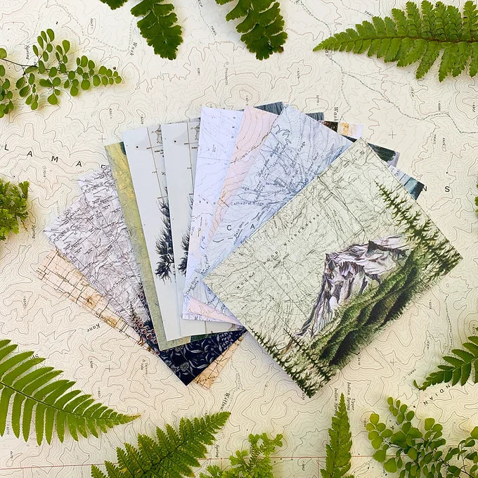 final switchback&#39;s greeting cards laid out on a topography map with foliage featuring contours of Oregon prints by artist Katie Jeanne Reim
