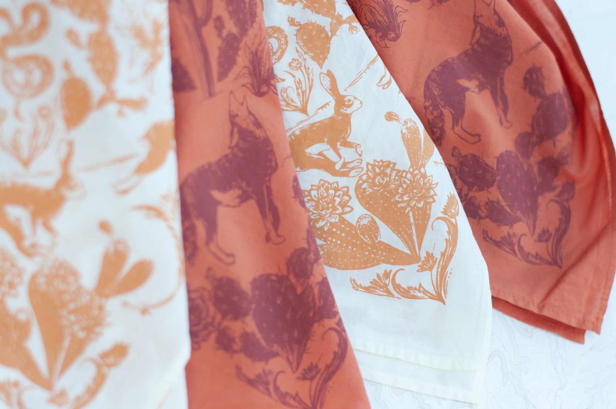 close-up of two final switchback cotton bandanas in Desert Nights cream and orange featuring artist Katie Jeanne Reim&#39;s prints
