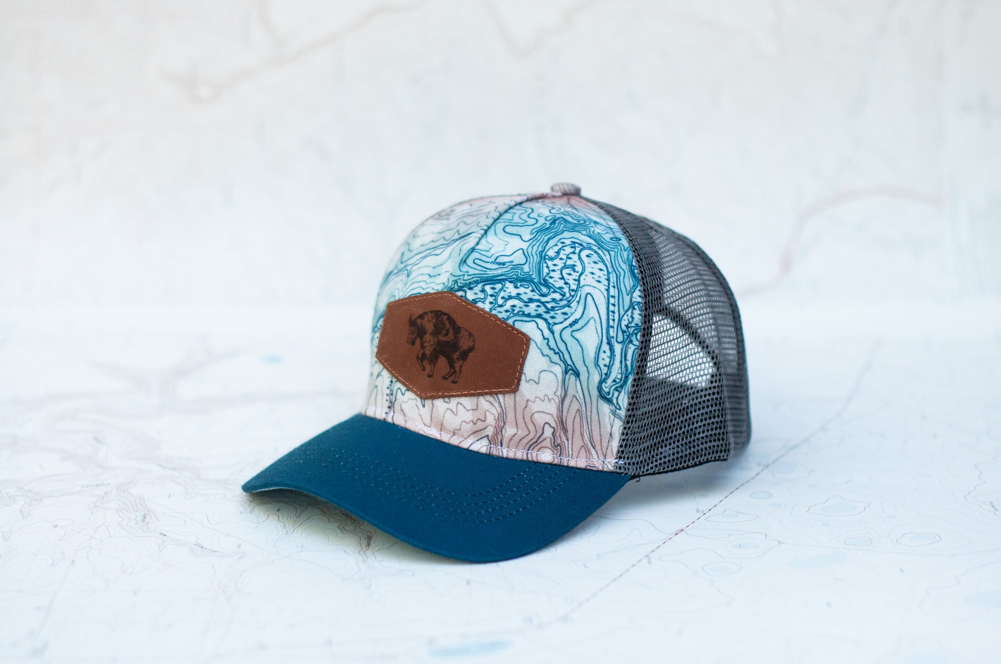 angle view of the final switchback trucker hat featuring artist Katie Jeanne Reim's Glacier Goat Summit print