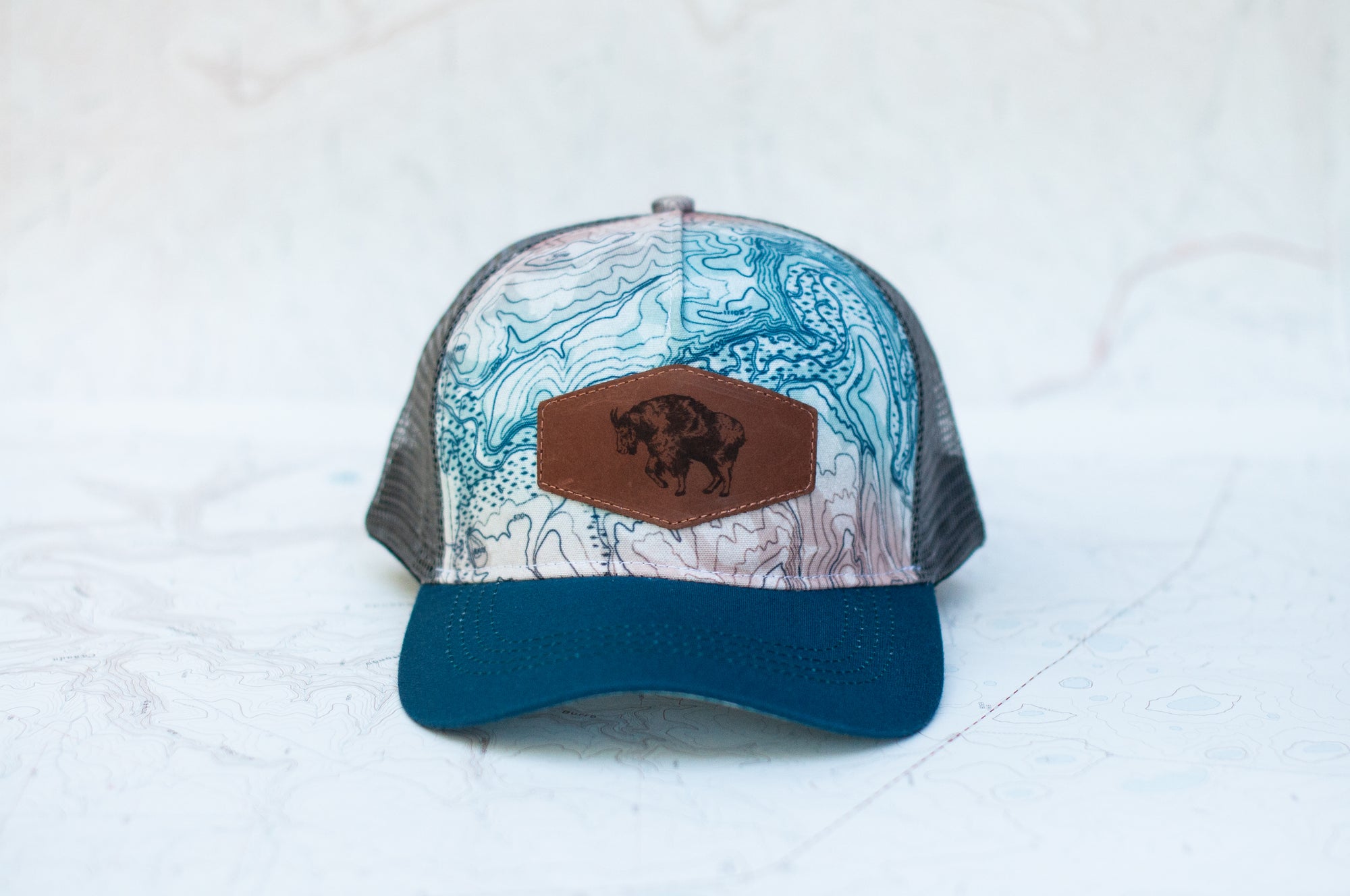 front view of the final switchback trucker hat featuring artist Katie Jeanne Reim&#39;s Glacier Goat Summit print