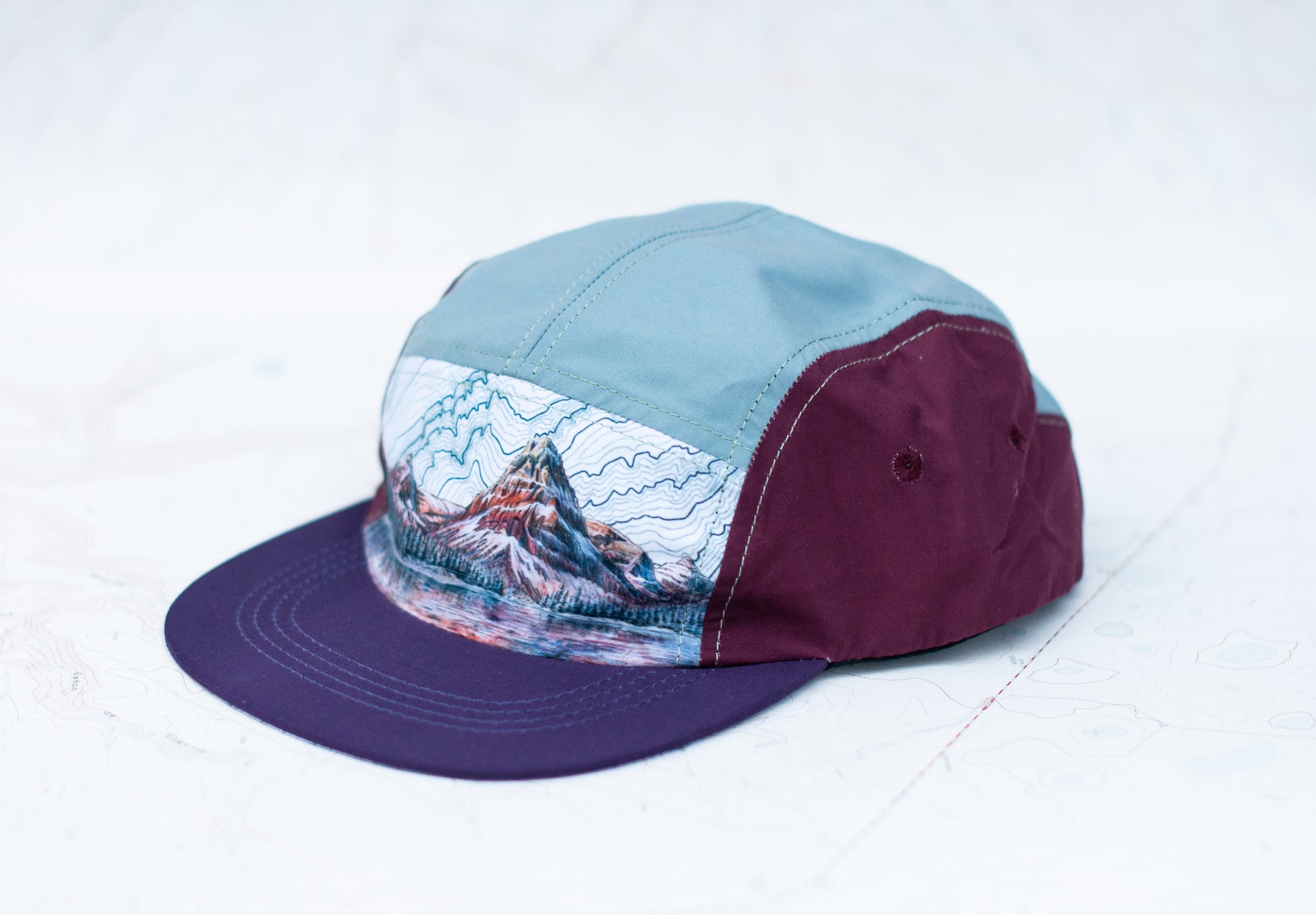 angle view of the final switchback 5-panel trail hat featuring artist Katie Jeanne Reim's Glacier Two Medicine print