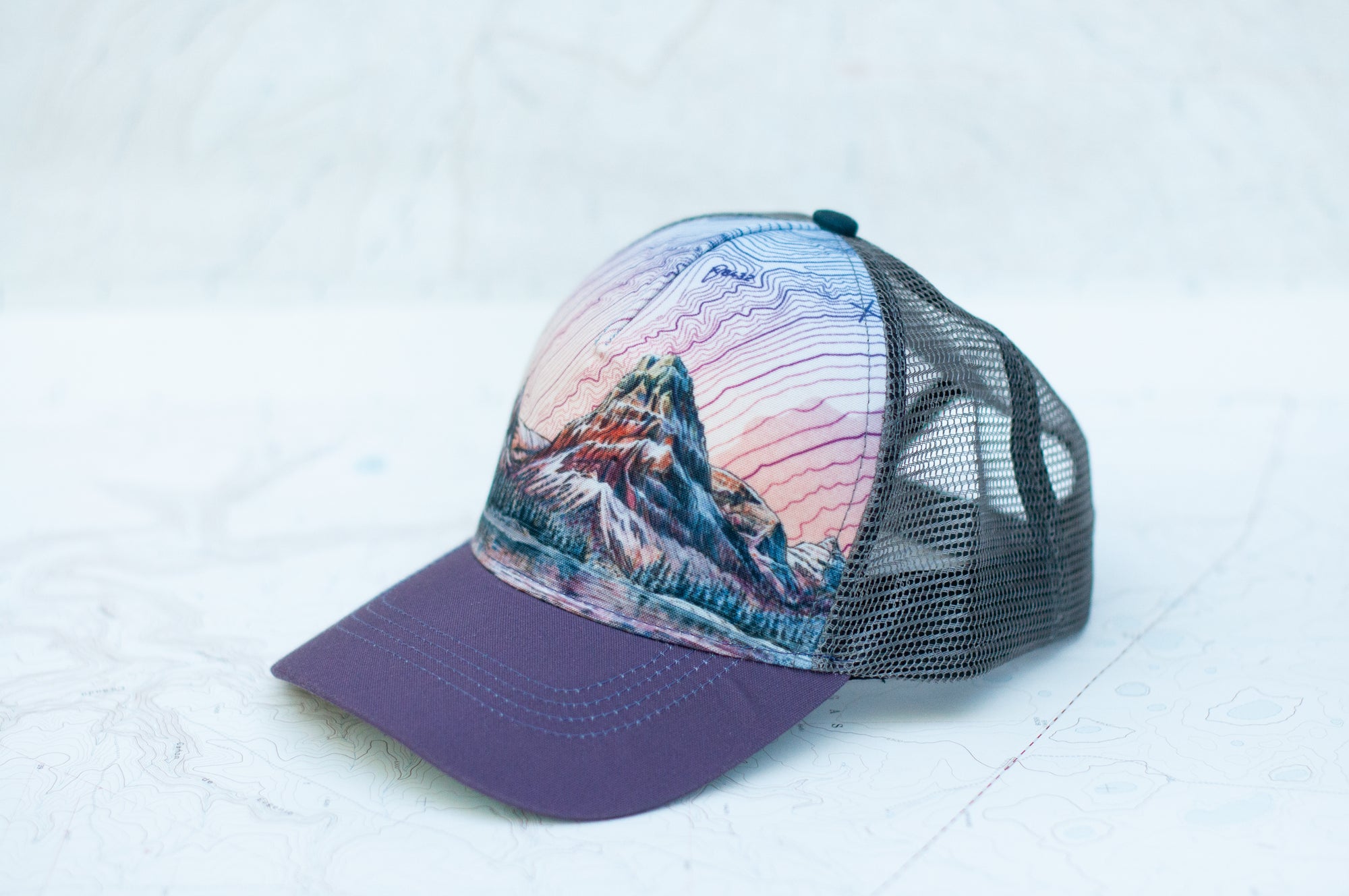 angle view of the final switchback trucker hat featuring artist Katie Jeanne Reim's Glacier Two Medicine print