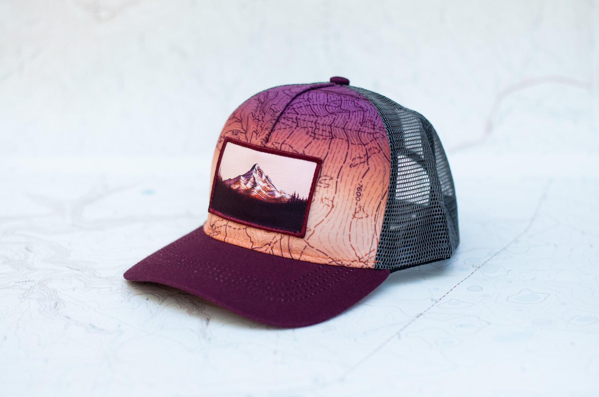 angle view of the final switchback trucker hat featuring artist Katie Jeanne Reim's mount hood sunset print