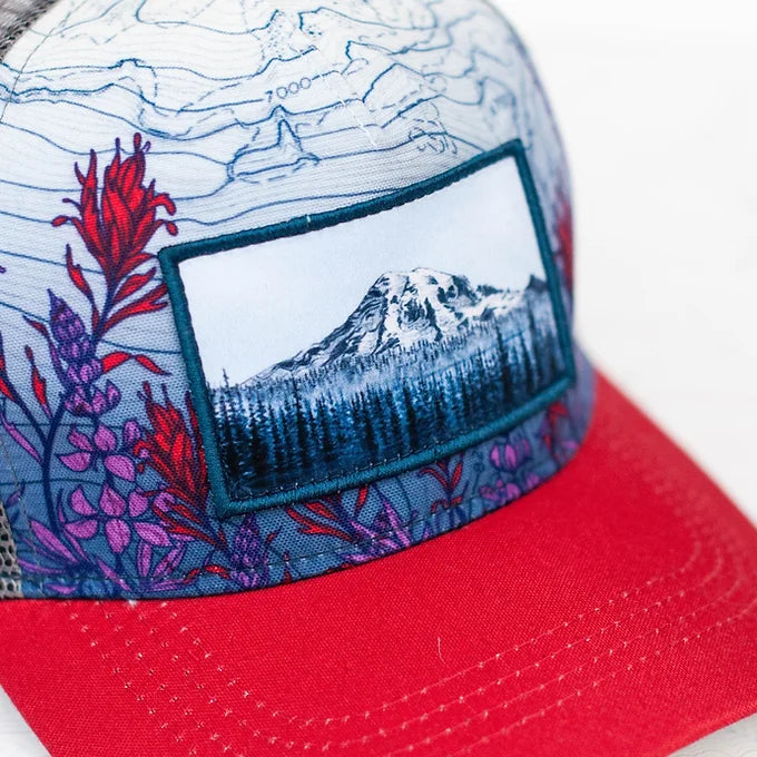 a close-up of the final switchback trucker hat featuring artist Katie Jeanne Reim&#39;s Mount Rainier Meadow print