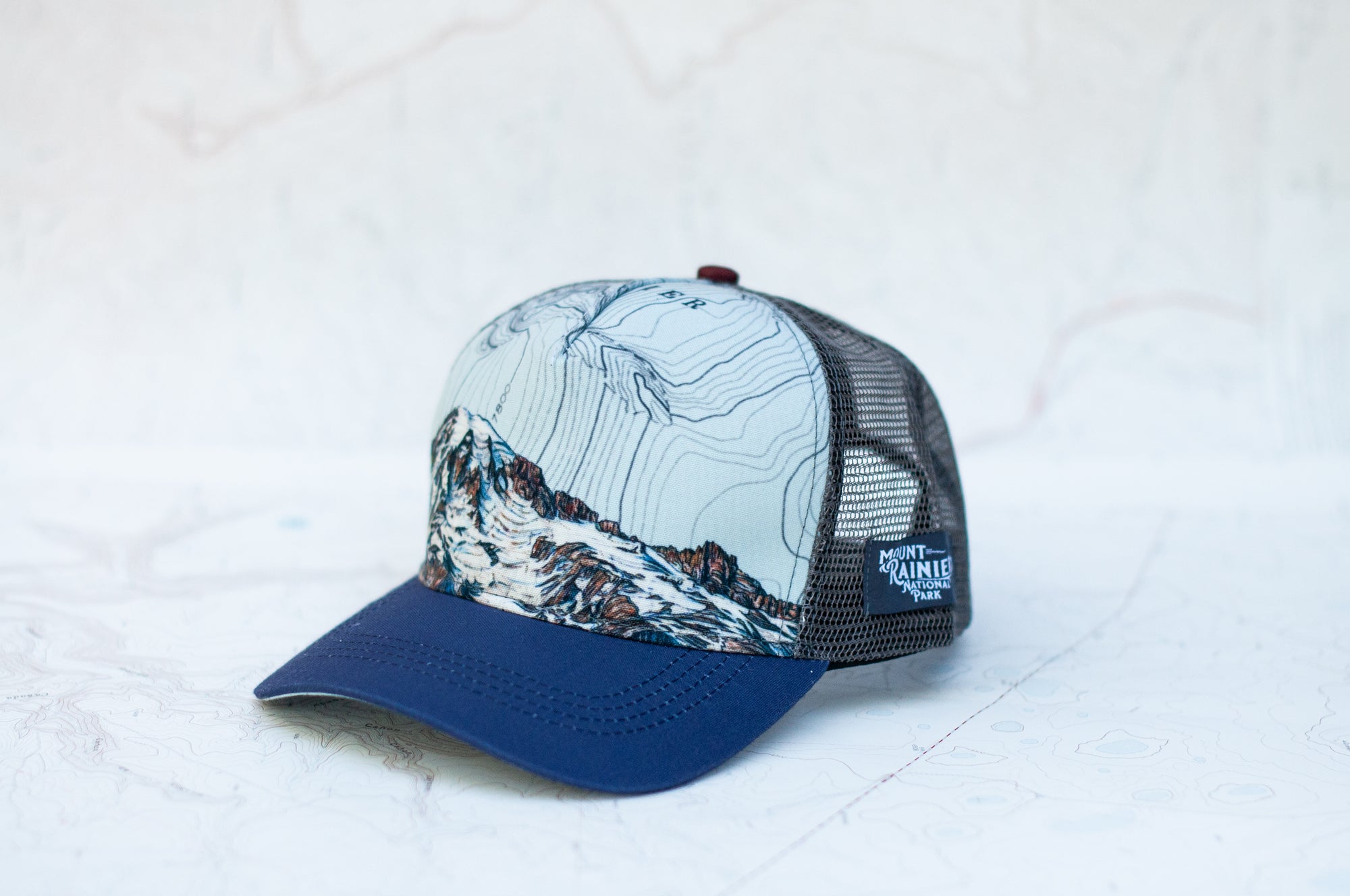 angle view of the final switchback trucker hat featuring artist Katie Jeanne Reim's Mount Rainier Summit print