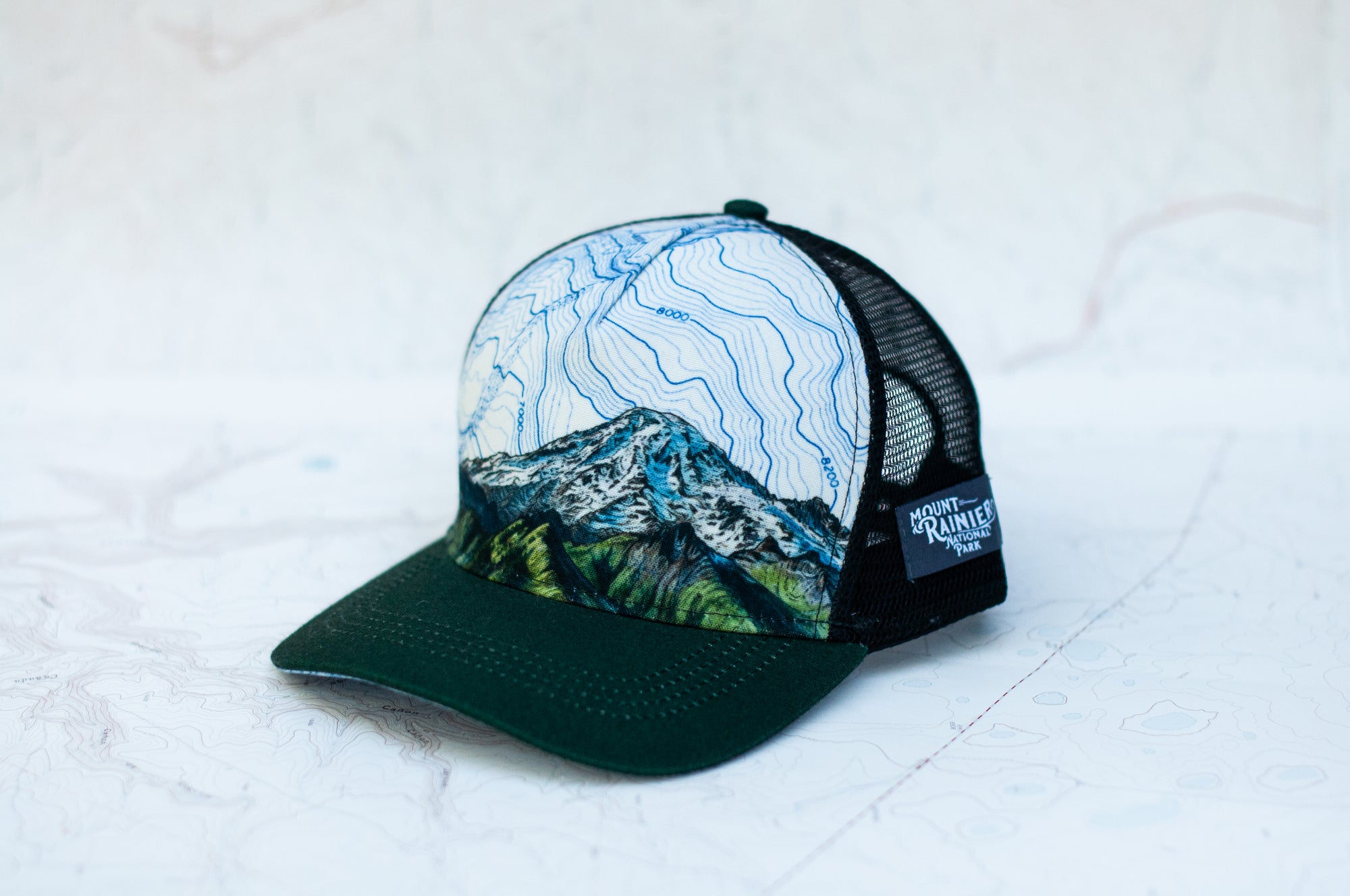 angle view of the final switchback trucker hat featuring artist Katie Jeanne Reim's Mount Rainier Tatoosh print