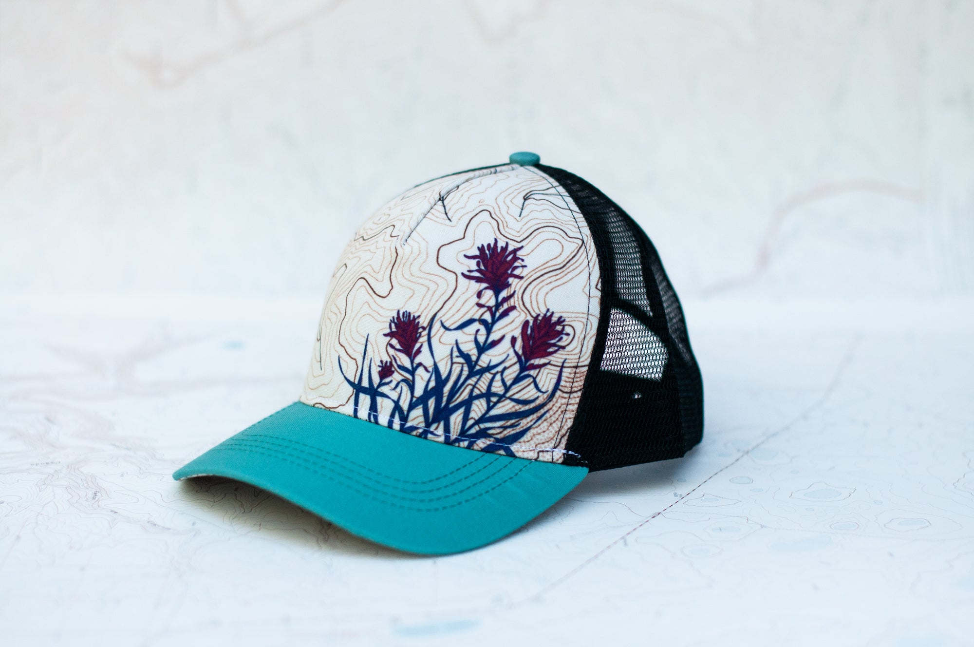 angle view of the final switchback trucker hat featuring artist Katie Jeanne Reim's paintbrush print