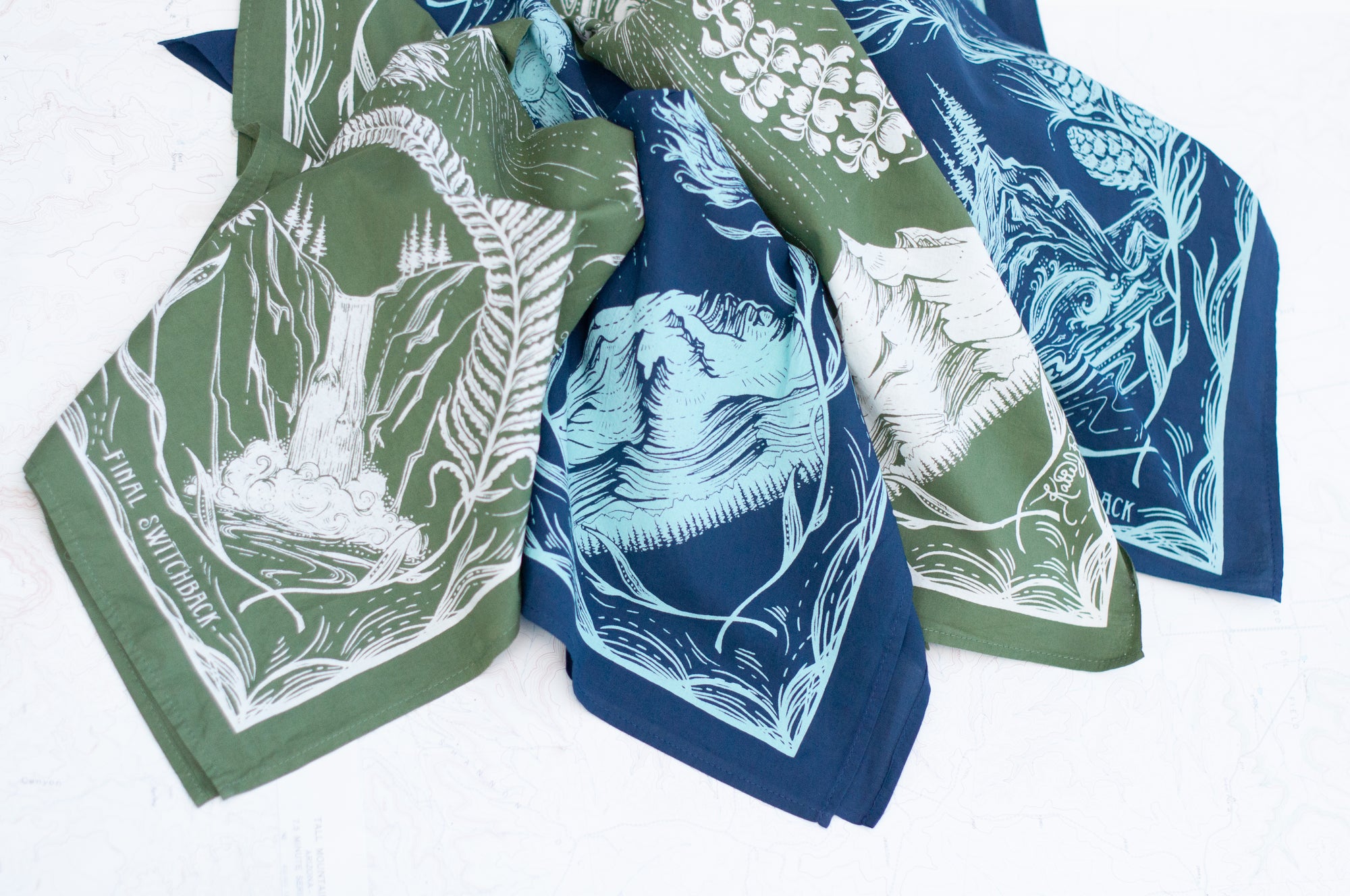 close-up of two final switchback cotton bandanas in PNW Green and PNW blue featuring artist Katie Jeanne Reim&#39;s prints