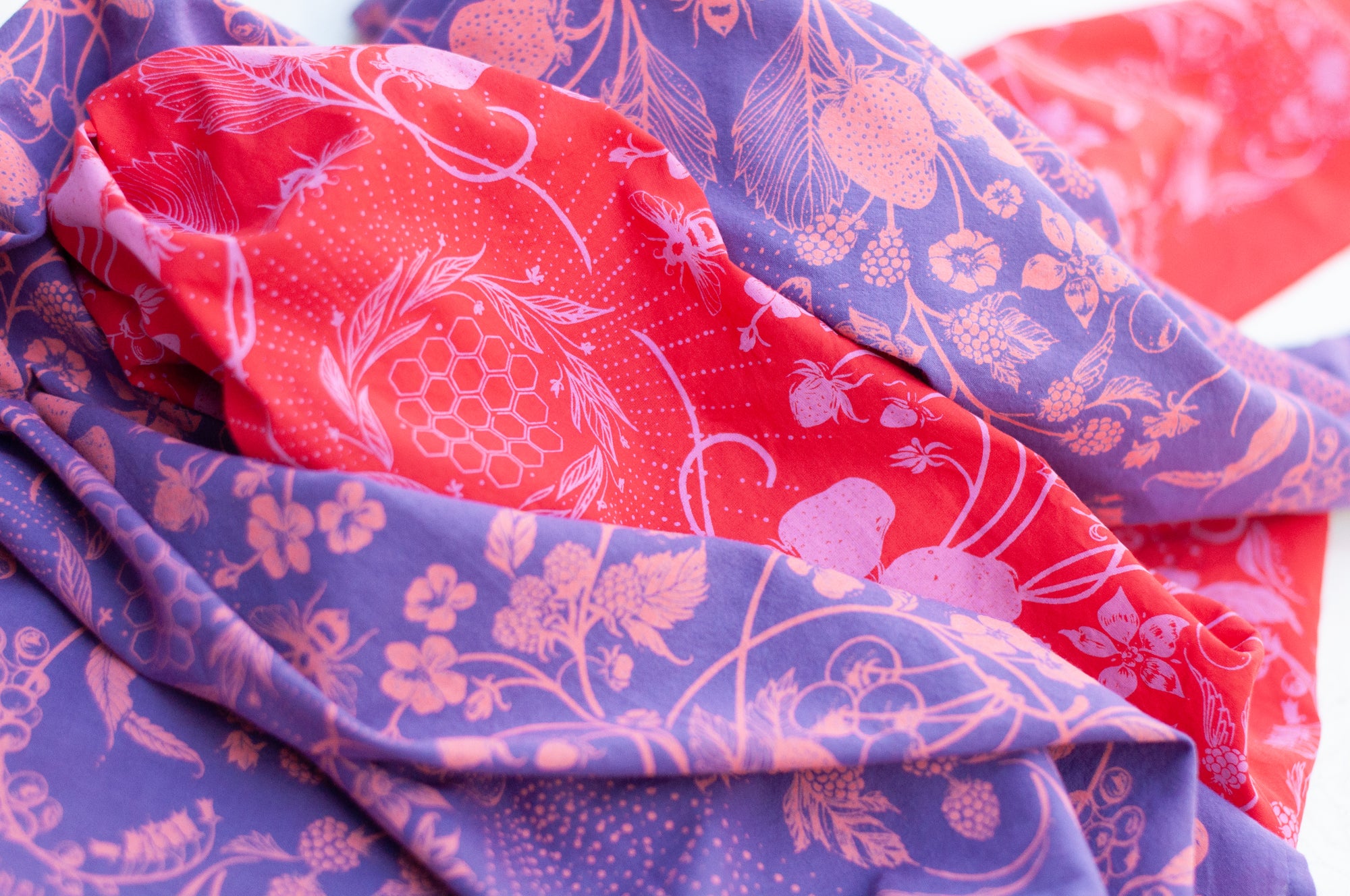 a close-up of two final switchback cotton bandanas in wildberry red and wildberry purple featuring artist Katie Jeanne Reim&#39;s prints
